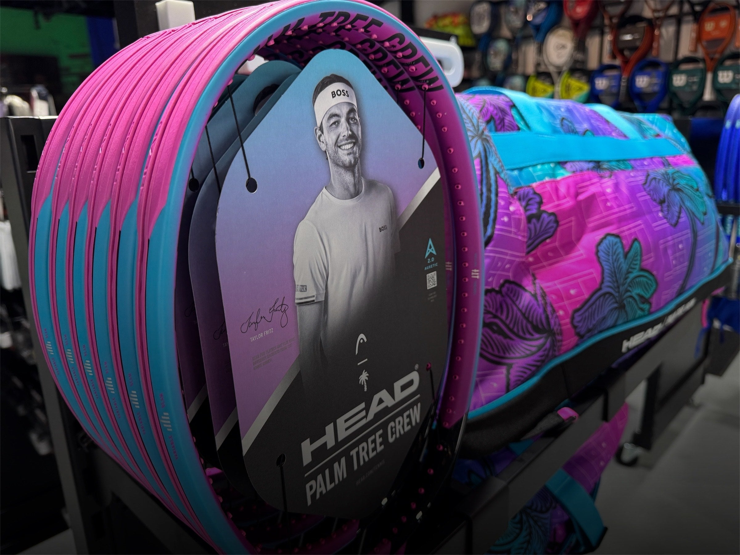 Stack of colorful tennis racket packages with a visible brand logo in a store setting.