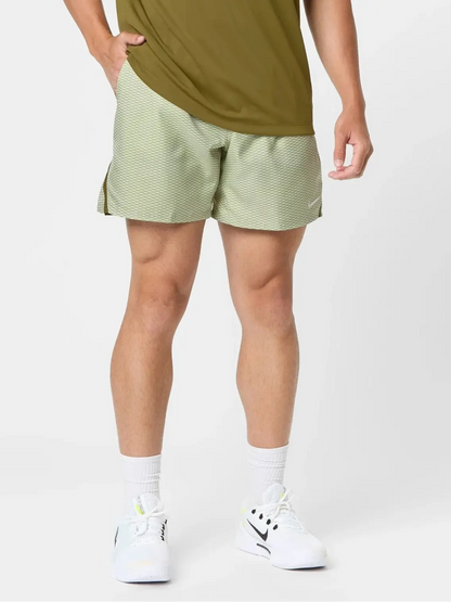 Man wearing a green Nike polo shirt and light green shorts on a white background